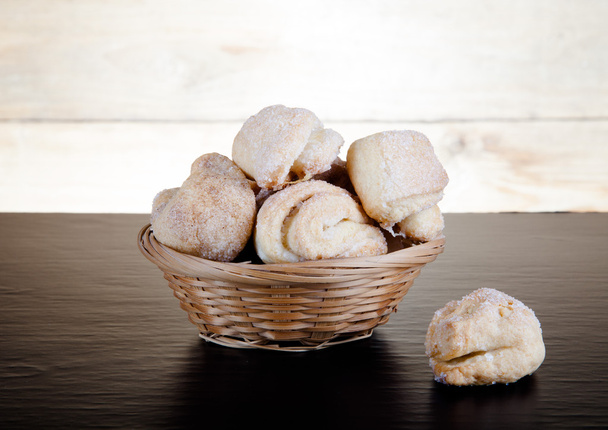Basket of cookie on a black table against old wooden background - Foto, immagini