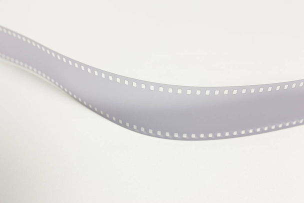 Translucent fragment of 35 mm movie on white surface. - 写真・画像
