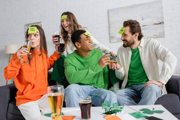 Positive multiethnic friends playing who i am game while celebrating saint patrick day at home  - Fotoğraf, Görsel