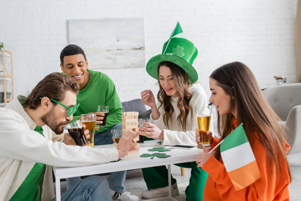 Multiethnic friends celebrating saint patrick day and playing wood blocks game at home  - Photo, Image