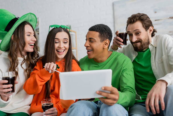 Multiethnic friends with beer using digital tablet during saint patrick day at home  - Photo, image