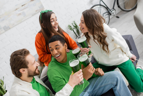 Interracial friends with green beer talking on saint patrick day  - 写真・画像