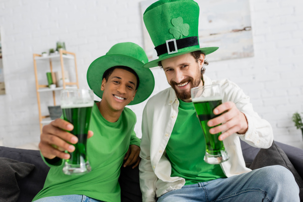 Hombres interraciales con sombreros verdes sosteniendo cerveza durante el día de San Patricio - Foto, imagen