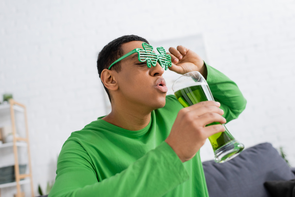 Uomo afroamericano in occhiali da sole partito in possesso di birra verde durante il giorno santo patrick - Foto, immagini