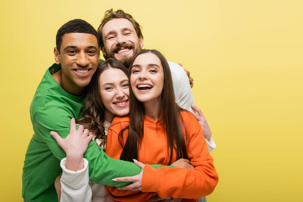 Smiling multiethnic friends hugging isolated on yellow  - Foto, Imagem