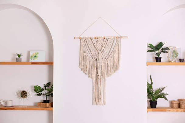 Modern composition of wabi sabi interior with shelf with home decoration and macrame. Stylish interior of living room and wall panel in style of Boho made of cotton threads using macrame technique - Fotoğraf, Görsel
