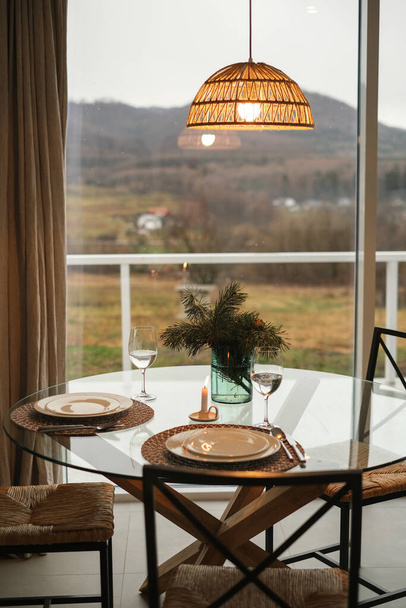 ужин подается стол в интерьере дома с панорамными окнами и видом на горы - Фото, изображение
