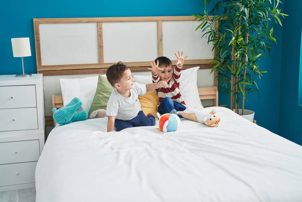 Two kids smiling confident sitting on bed at bedroom - Zdjęcie, obraz