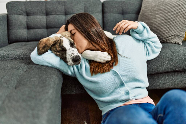 Junge Frau umarmt Hund, der zu Hause auf dem Boden sitzt - Foto, Bild