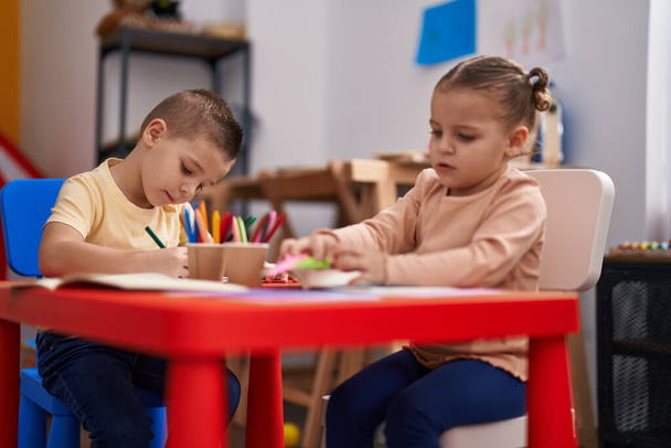 Two kids preschool students sitting on table drawing on paper at kindergarten - Фото, изображение