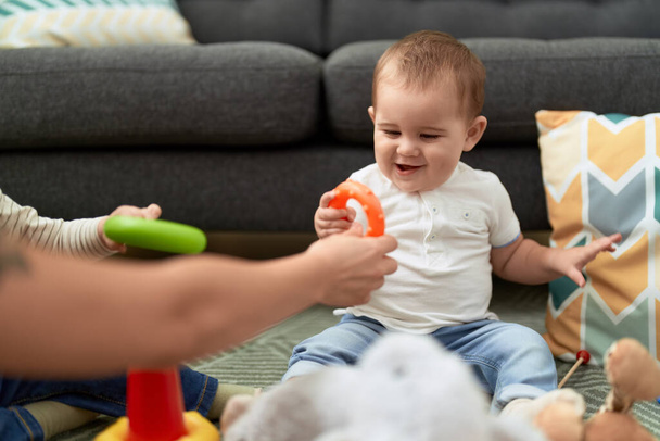 Sevimli çocuk evde yerde oturmuş oyuncaklarla oynuyor. - Fotoğraf, Görsel