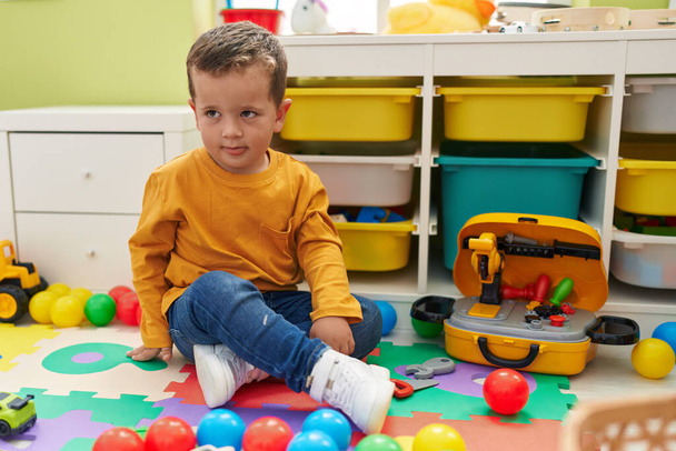 Adorável menino caucasiano brincando com bolas sentadas no chão no jardim de infância - Foto, Imagem