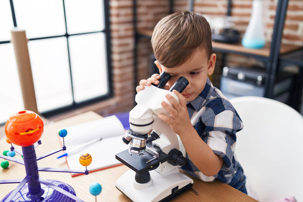 Entzückende hispanische Junge Student mit Mikroskop im Labor Klassenzimmer - Foto, Bild