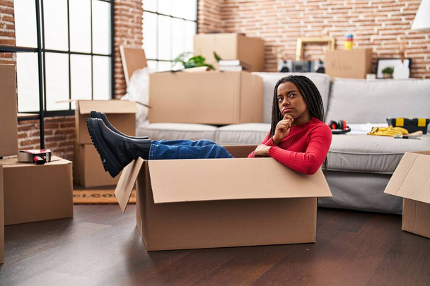 African american woman packing cardboard box at new home - Foto, imagen