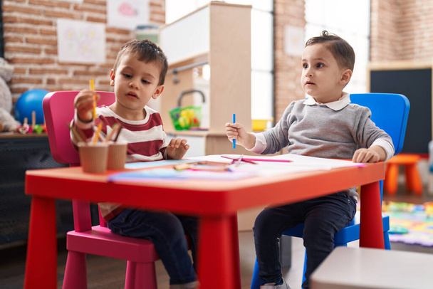 Δύο παιδιά προσχολικής ηλικίας που κάθονται στο τραπέζι ζωγραφίζοντας σε χαρτί στο νηπιαγωγείο - Φωτογραφία, εικόνα