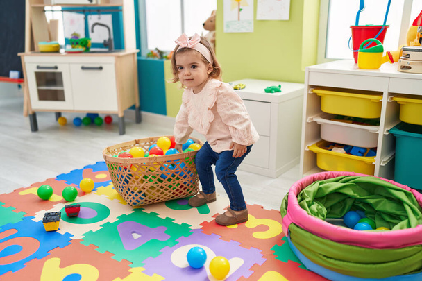 Adorable blonde toddler playing with balls sitting on floor at kindergarten - Foto, immagini
