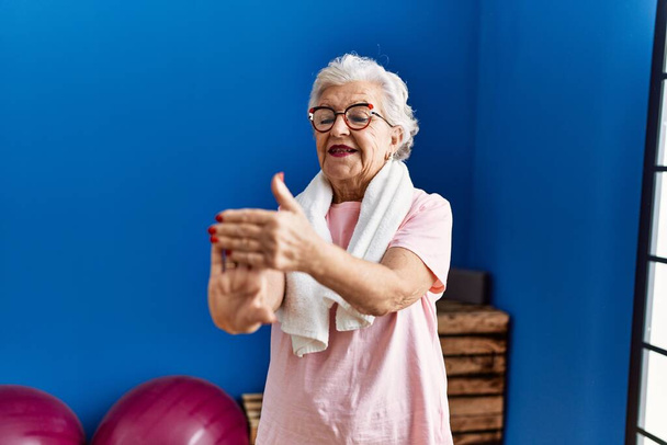 Idősebb ősz hajú nő, aki sportruházatot visel, magabiztosan mosolyog a sportközpontban. - Fotó, kép