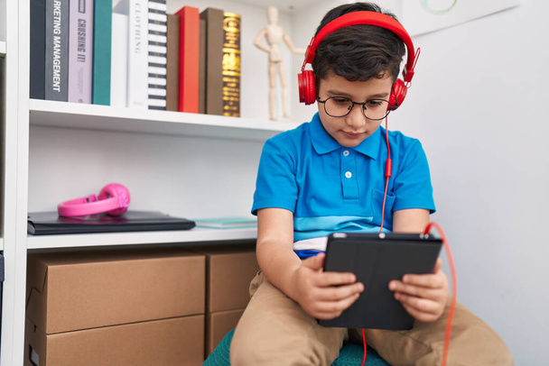 adorabile ispanico ragazzo studente guardando video su touchpad a biblioteca scuola - Foto, immagini
