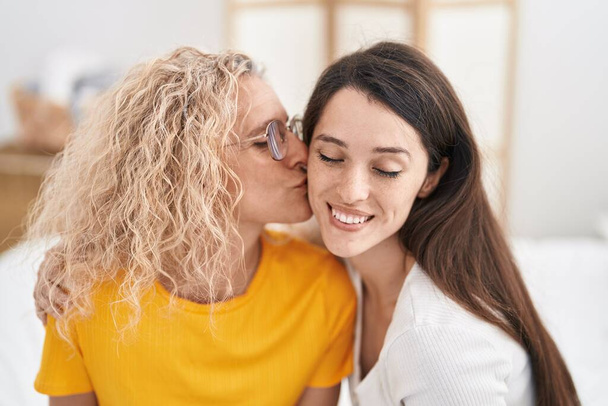 Kaksi naista äiti ja tytär halaavat toisiaan ja suutelevat makuuhuoneessa - Valokuva, kuva