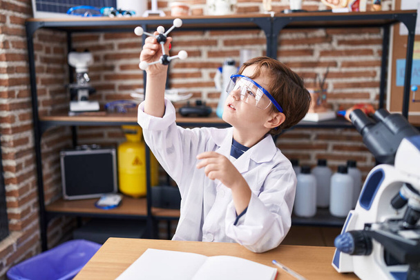 Suloinen latino poika opiskelija etsii molekyylejä laboratoriossa luokkahuoneessa - Valokuva, kuva
