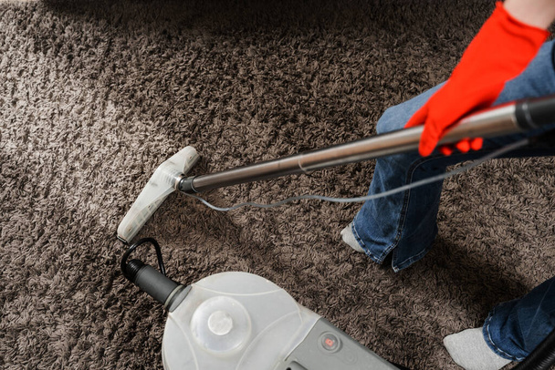 Housekeeper is extracting dirt from carpet using dry cleaning extractor mop machine. Cleaner girl is cleaning carpet with mop extraction machine for dry clean upholstered furniture - Photo, Image
