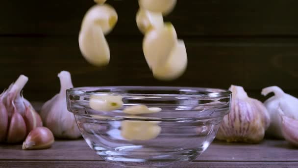 Fresh garlic clove peeled falling in glass bowl. The raw garlic is one of the most popular ingredients of the basic recipes with nutritional properties, infamous aroma and health benefits. Slow motion - Metraje, vídeo