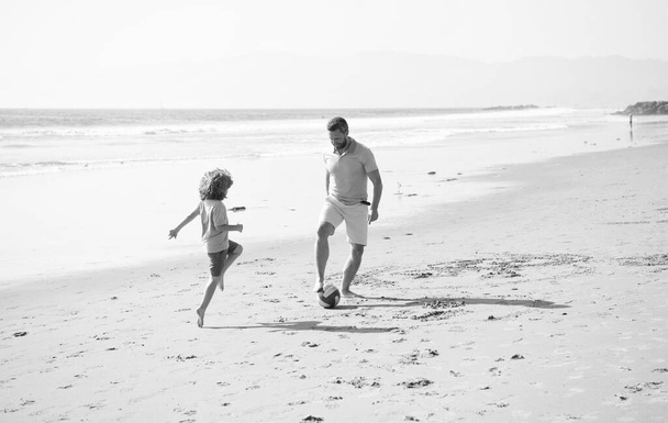χαρούμενος πατέρας και γιος παίζουν ποδόσφαιρο διασκεδάζοντας στις καλοκαιρινές αμμώδεις παραλίες οικογενειακές διακοπές, τον αθλητισμό. - Φωτογραφία, εικόνα