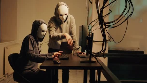 Mysterious spies working on phishing and cryptojacking, trying to break into government server and steal valuable data. Team of hackers with anonymous masks hacking online system. - Felvétel, videó