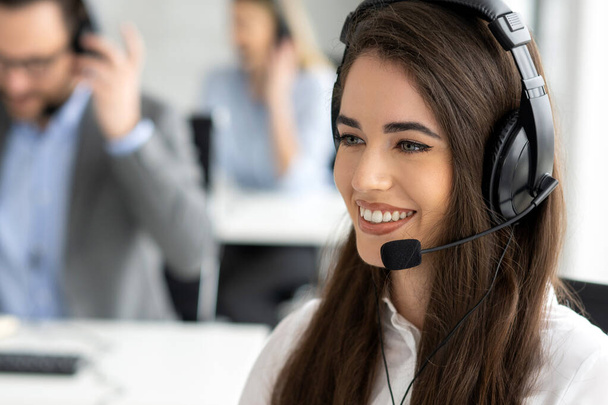 Headshot of beautiful young woman talking to client in a call center. - Foto, Imagem