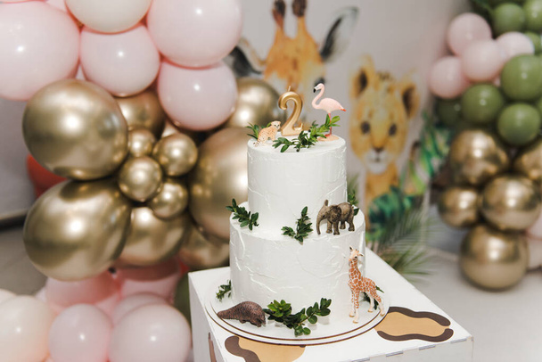 Animal themed birthday cake. Number 2 birthday candle in a cake. Two Tier Beautiful Animal Cake - flamingo, giraffe, leopard. Happy two years. - Photo, Image