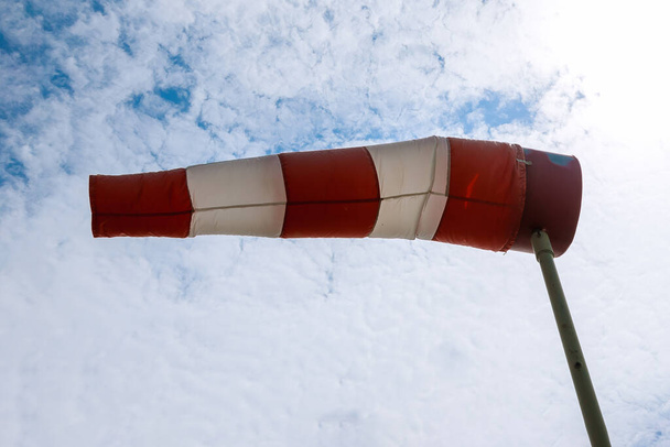 Eine große rot-weiß gestreifte Windsack vor blauem Himmel - Foto, Bild
