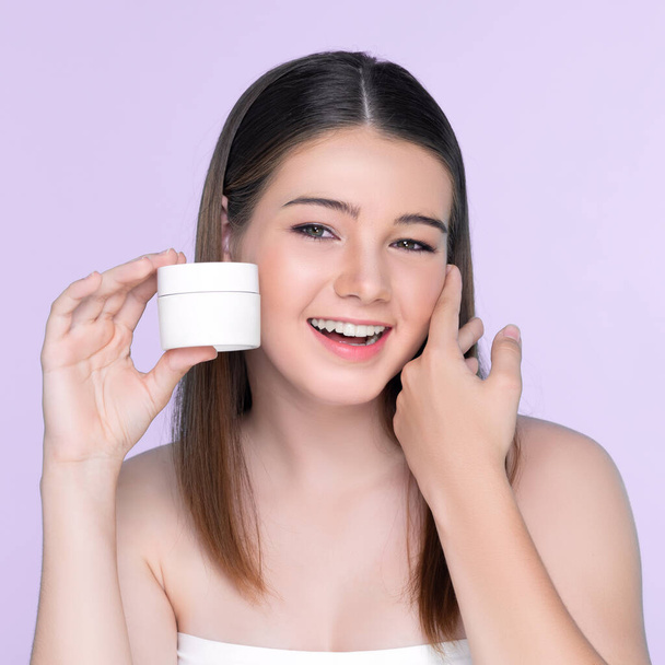 Young charming girl with natural beauty, perfect smooth skin hold lotion, cream, moisturizer jar. Beautiful girl show skincare product smiling on isolated background. - Фото, изображение