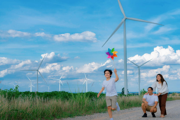 Progressive happy family enjoying their time at wind farm for green energy production concept. Wind turbine generators provide clean renewable energy for eco-friendly purposes. - Photo, Image