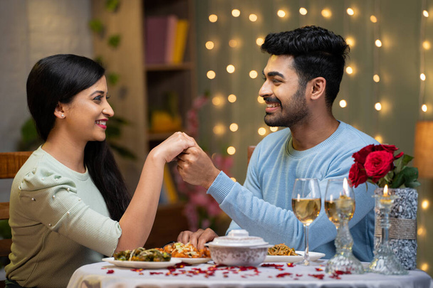 młody mężczyzna oświadczając się dziewczynie trzymając się za ręce przy kolacji przy świecach - koncepcja miłości lub emocji, walentynki i romantyczna para. - Zdjęcie, obraz