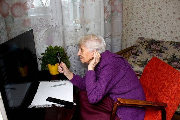 La pobre mujer mayor viendo la televisión en casa. - Foto, imagen