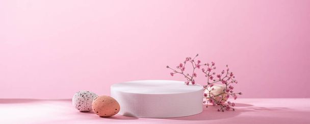 Abstract empty white podium with Easter quail eggs and spring flowers on pink background. Mock up stand for product presentation. Minimal concept. Advertising template banner - Fotoğraf, Görsel