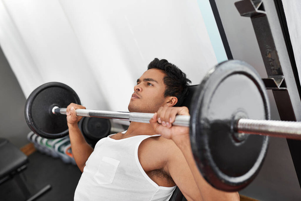 These muscles were built for power. A young ethnic man lifting weights at the gym - 写真・画像