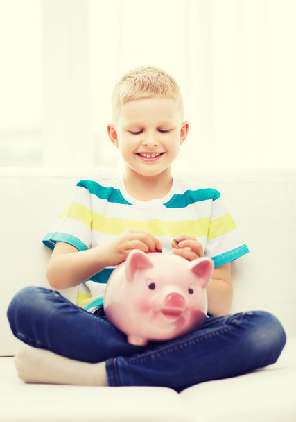 smiling little boy with piggy bank at home - Fotó, kép