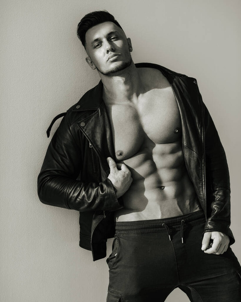 Black and white portrait of handsome man in leather jacket. Sexy male model in brutal look. Biker style shot of muscular guy. - Photo, Image