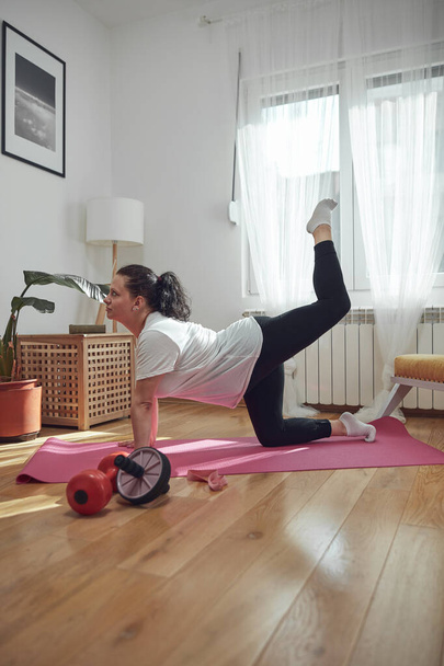 Woman training inside the living room, exercising at home. - Fotografie, Obrázek