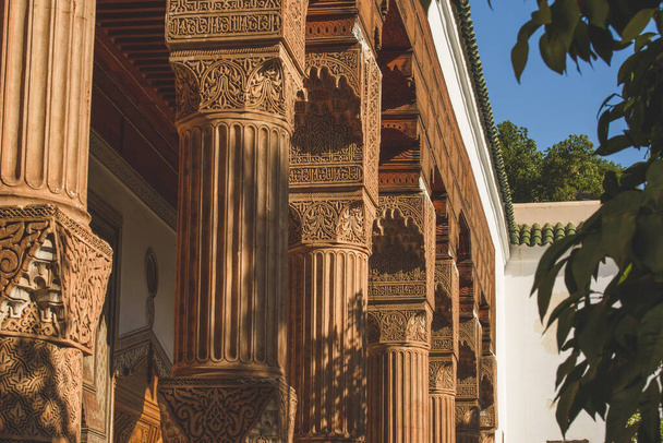 Η περίπλοκη αρχιτεκτονική του Μαρακές, Μαρόκο ζωντανεύει μέσα στη ζωντανή βλάστηση των πορτοκαλιών. Τα ευωδιαστά άνθη τους προσθέτουν μια νότα φυσικής ομορφιάς στις διαχρονικές δομές της πόλης, δημιουργώντας ένα αρμονικό μείγμα τεχνητής κομψότητας. - Φωτογραφία, εικόνα