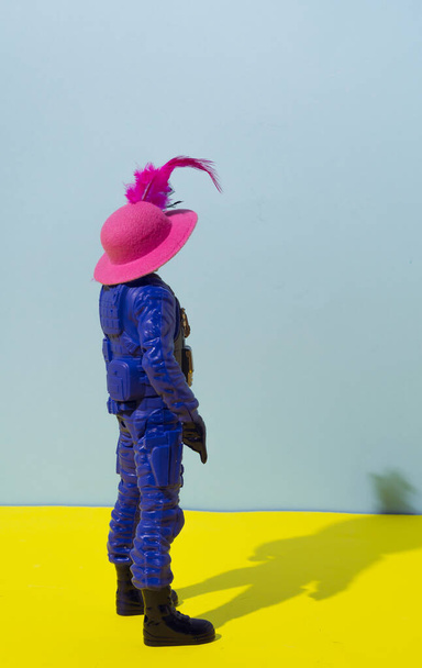 A policeman in uniform with a pink lady's hat on his head. Conceptual setting inspired by the famous Banksy, mural artist and pacifist. Cheerful colors against the corrupt government. - Foto, Imagen