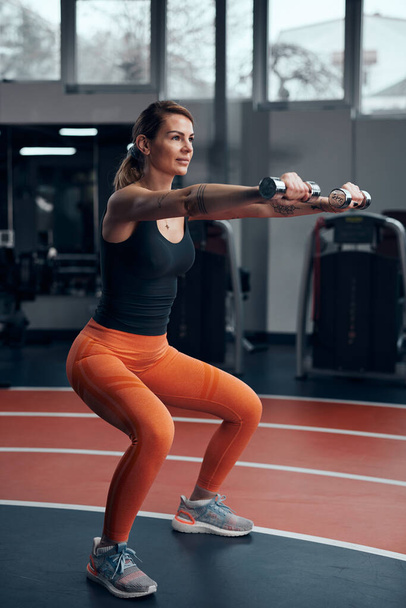 Αθλητική γυναίκα στο γυμναστήριο άσκηση με ελαφρύ βαρίδι. - Φωτογραφία, εικόνα