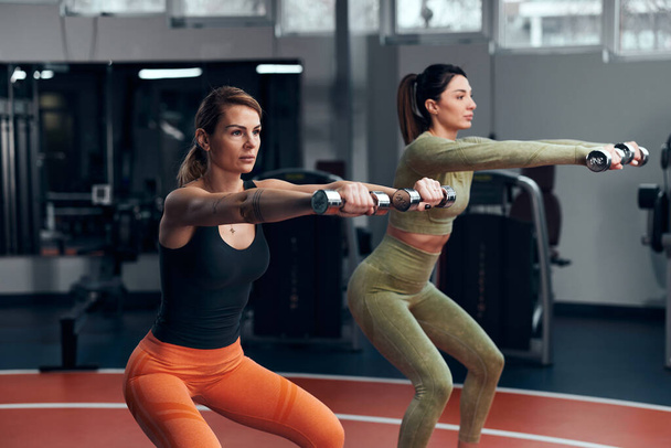 Αθλητικές γυναίκες σε γυμναστήριο άσκηση με ελαφρύ βαρίδι. - Φωτογραφία, εικόνα