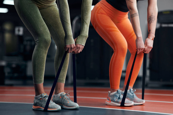 Sportieve vrouwen in de sportschool trainen met elastische elastische elastiekjes. - Foto, afbeelding