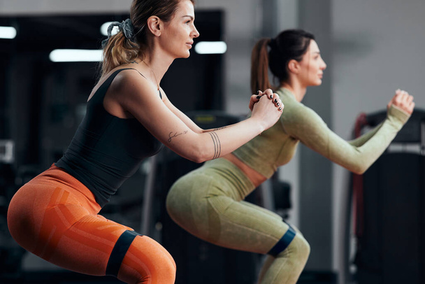 Спортивные женщины в тренажерном зале с резинкой эластичного сопротивления. - Фото, изображение