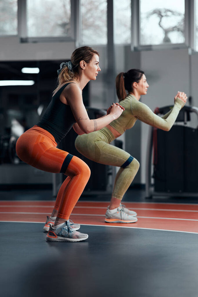 Spor salonundaki sporcu kadınlar elastik direnç lastiğiyle egzersiz yapıyorlar.. - Fotoğraf, Görsel