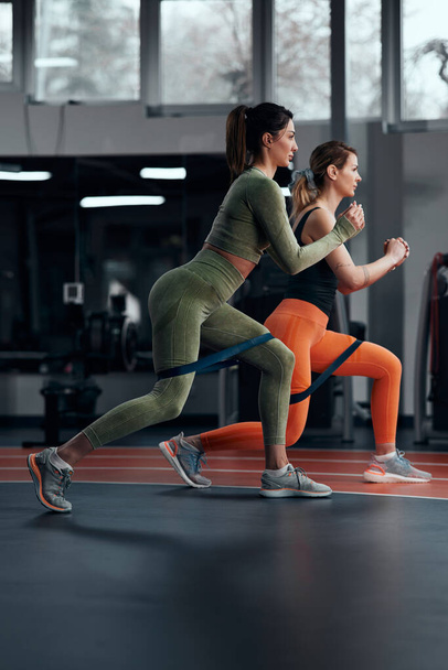 Sportos nők edzőteremben gyakorló rugalmas ellenállás gumiszalaggal. - Fotó, kép