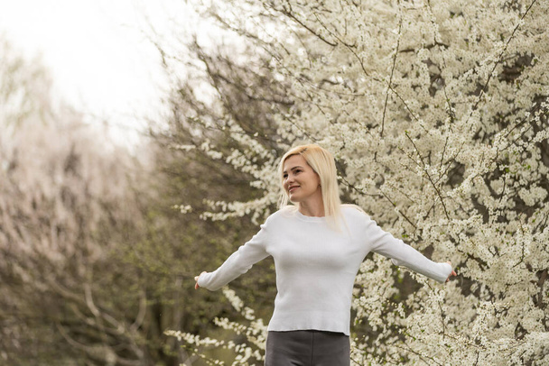 Portrait of a young woman in a blooming orchard. Blonde woman. - Photo, Image