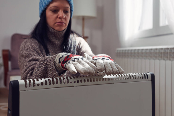 Soğuk bir kış gününde, ceketli, kazaklı ve eldivenli bir kadın. Enerji ve gaz krizi, soğuk oda, ısıtma sorunları.. - Fotoğraf, Görsel